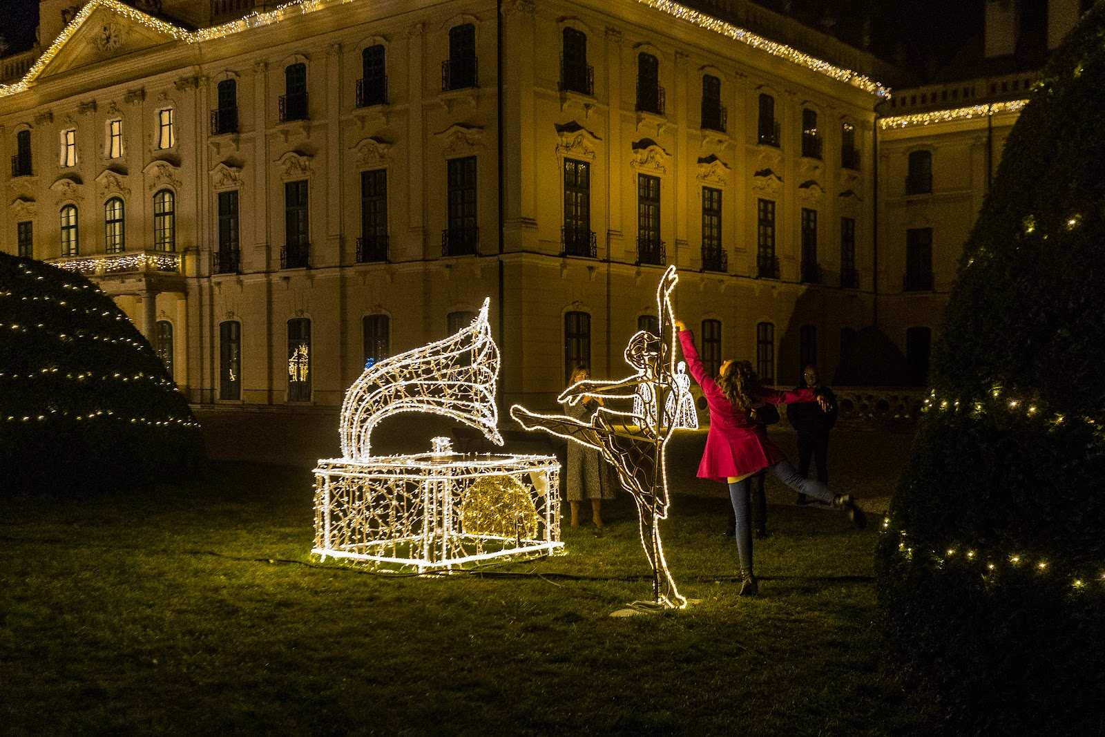 Die beleuchtete Schlossfassade, davor eine Tänzerinnenfigur und eine Truhe aus Licht