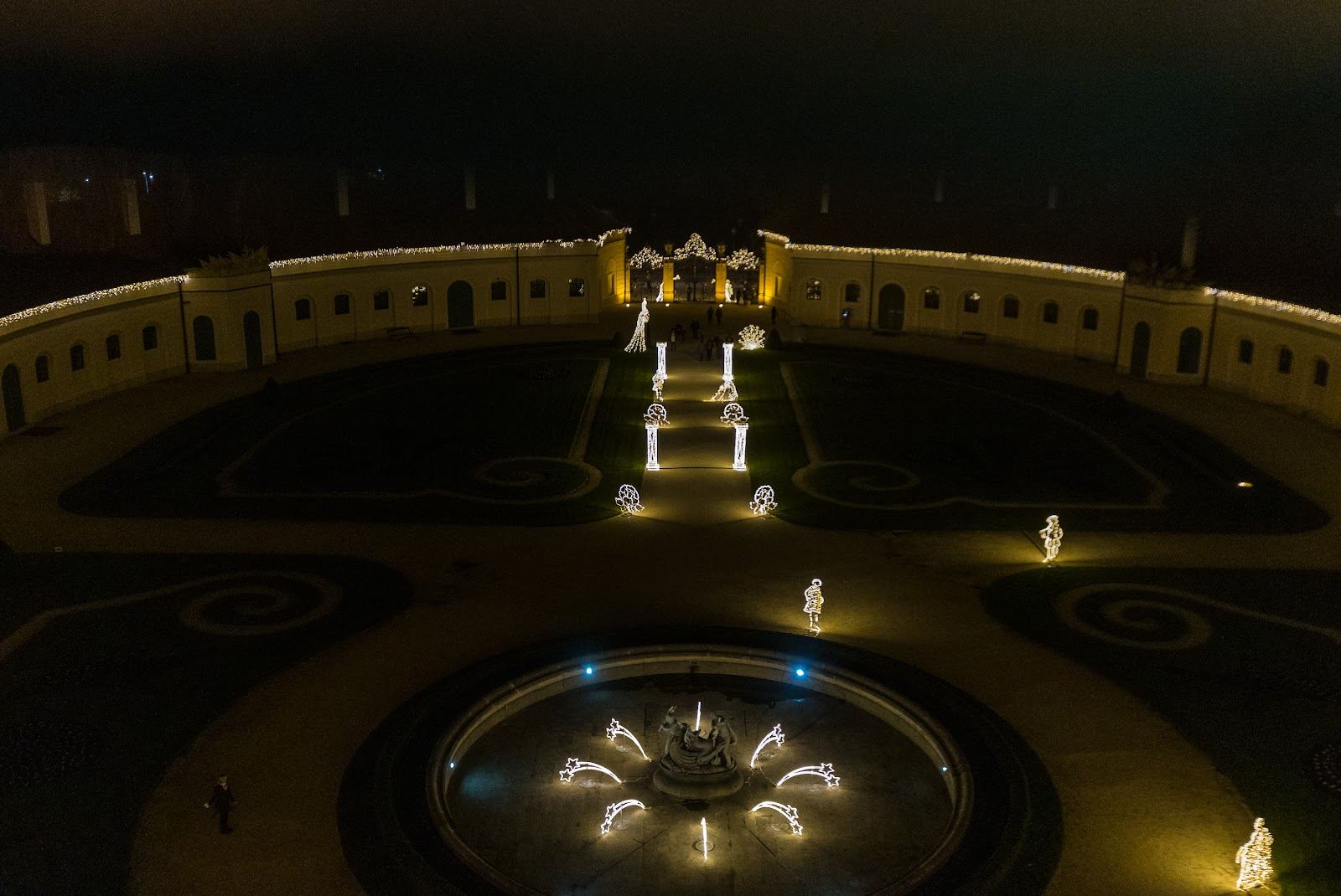 Blick von oben auf den beleuchteten Ehrenhof des Schlosses Esterházy mit dem Springbrunnen bei Nacht